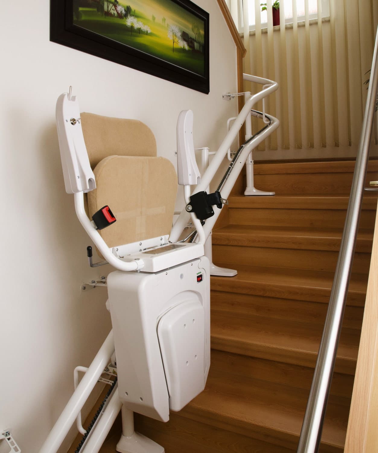 Lehner Alpha Zusammengeklappter Treppenlift mit beigem Sitzpolster an einer Holztreppe im Innenbereich.