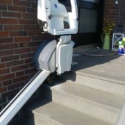 Außen-Treppenlift an einer kurzen Steintreppe vor dem Eingang eines Hauses montiert.