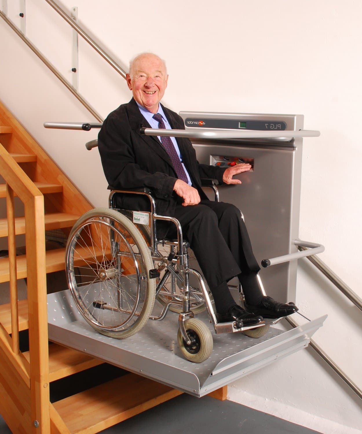 Plattformlift Älterer Mann im Rollstuhl fährt mit einem Plattformlift eine Treppe hinauf und lächelt