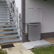 Plattformlift Plattformlift im Außenbereich an einer Metalltreppe neben einem Wohnhaus installiert.