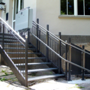 Plattformlifte-2-1 Plattformlift an einer Außentreppe mit schwarzem Metallgeländer vor einem Wohnhaus.