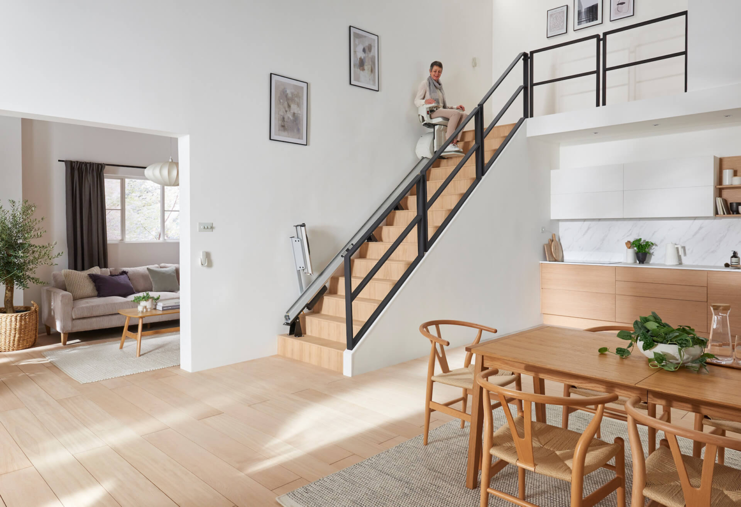 Treppenlift wird in einem modernen Haus benutzt Ältere Frau fährt mit einem Treppenlift eine moderne Holztreppe hinauf.