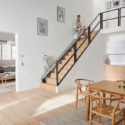 Treppenlift wird in einem modernen Haus benutzt Ältere Frau fährt mit einem Treppenlift eine moderne Holztreppe hinauf.