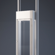 Moderner Plattformlift mit verglaster Kabine und schlanker Metallrahmen-Konstruktion vor dunklem Hintergrund.