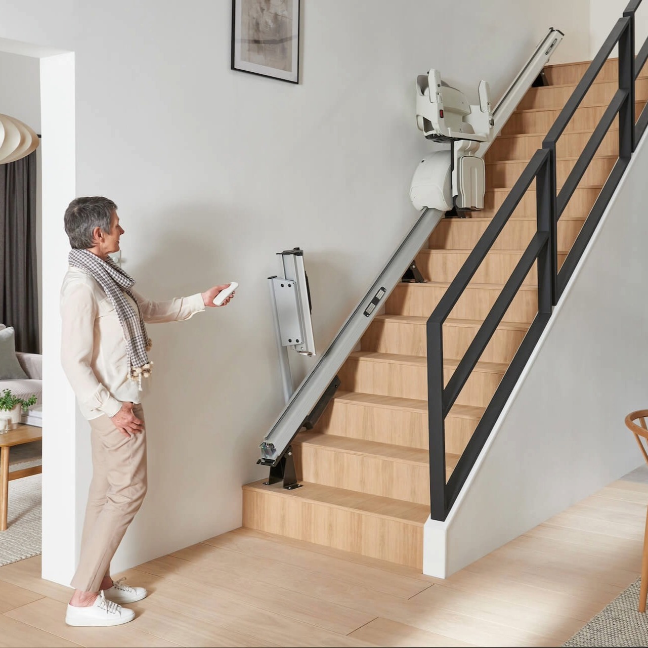 Maße für den Einbau von Treppenliften bei Bittcher Liftsysteme Person steht vor einem Treppenlift an einer geraden Innentreppe als Beispiel für Maße und Einbauplanung